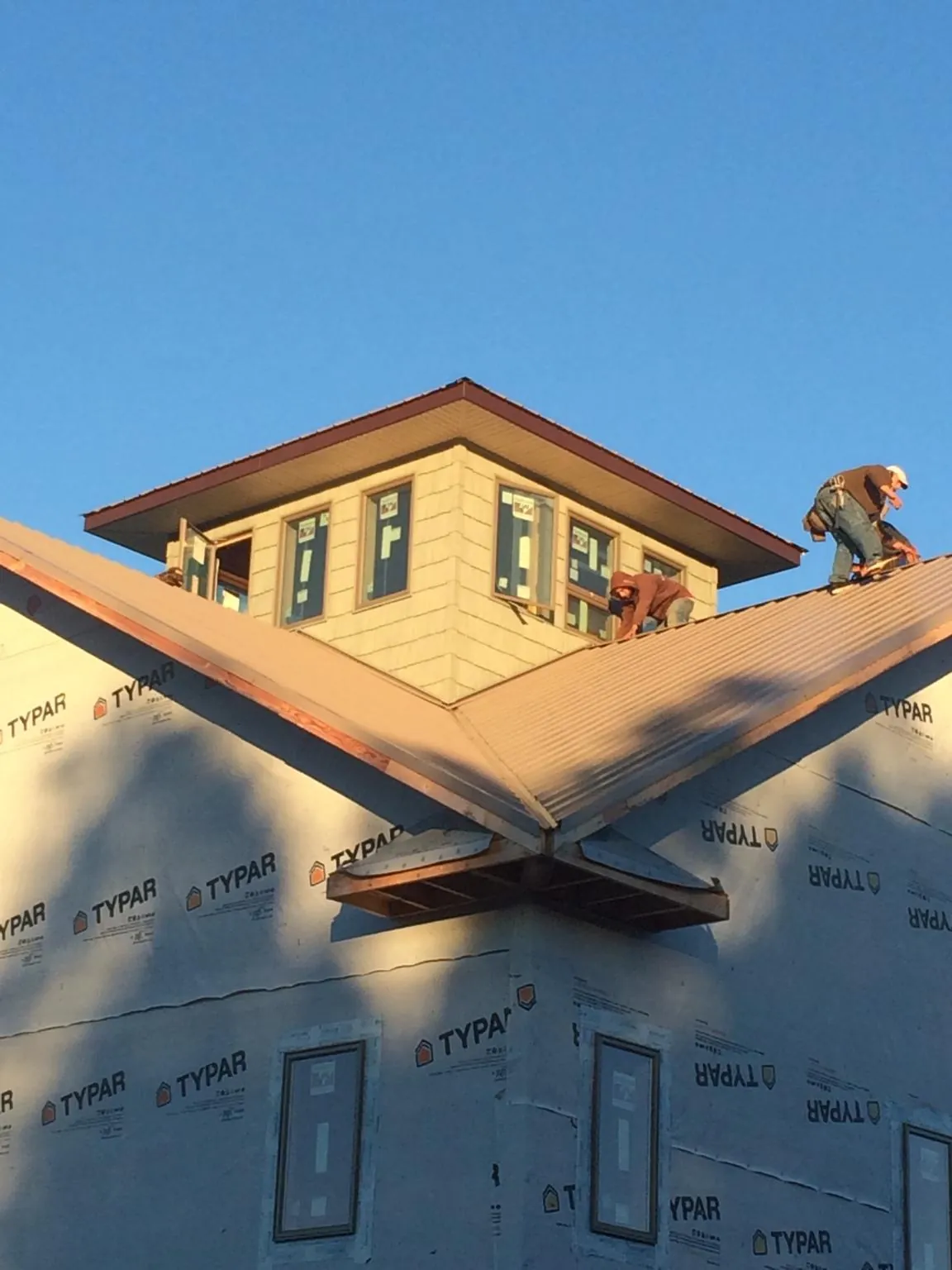 Roofers working around a rooftop cupola on a new metal roof at sunset — Roof Waterproofing in Deadwood by Roofing Brothers